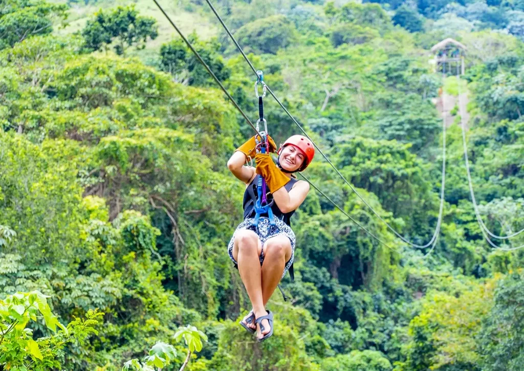 Mulher sorridente a desfrutar de um emocionante slide (zipline) pela floresta tropical em Punta Cana, República Dominicana – aventura inesquecível com a Best Tour Punta Cana